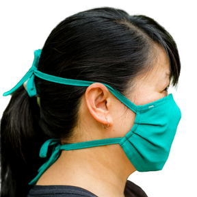 Side view of a teal face mask on a woman with a ponytail.